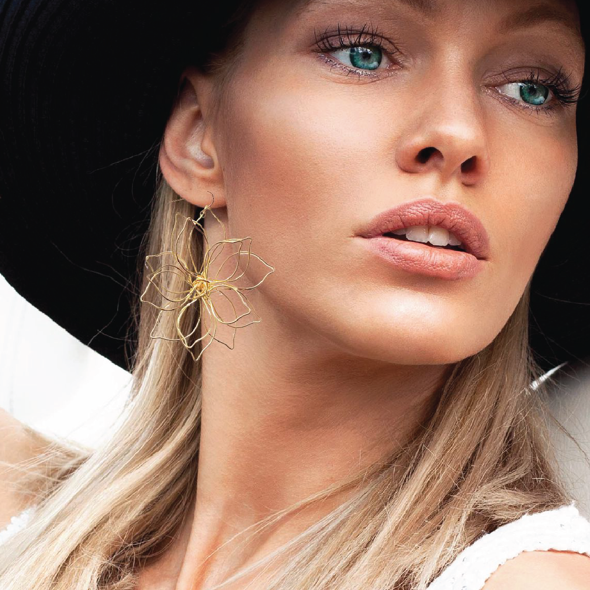 Close-up of a woman wearing gold earrings with a black background